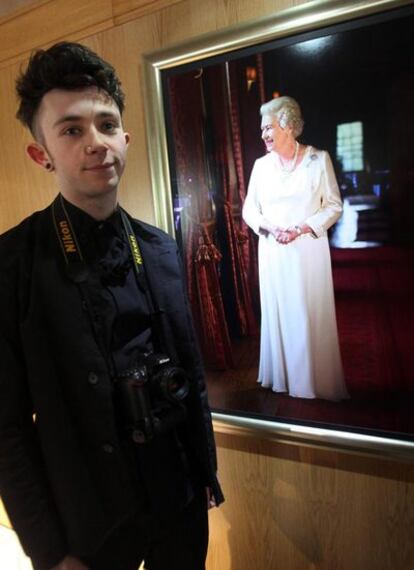 El joven Shaun Murawski, frente al retrato que le realizó a la reina Isabel.