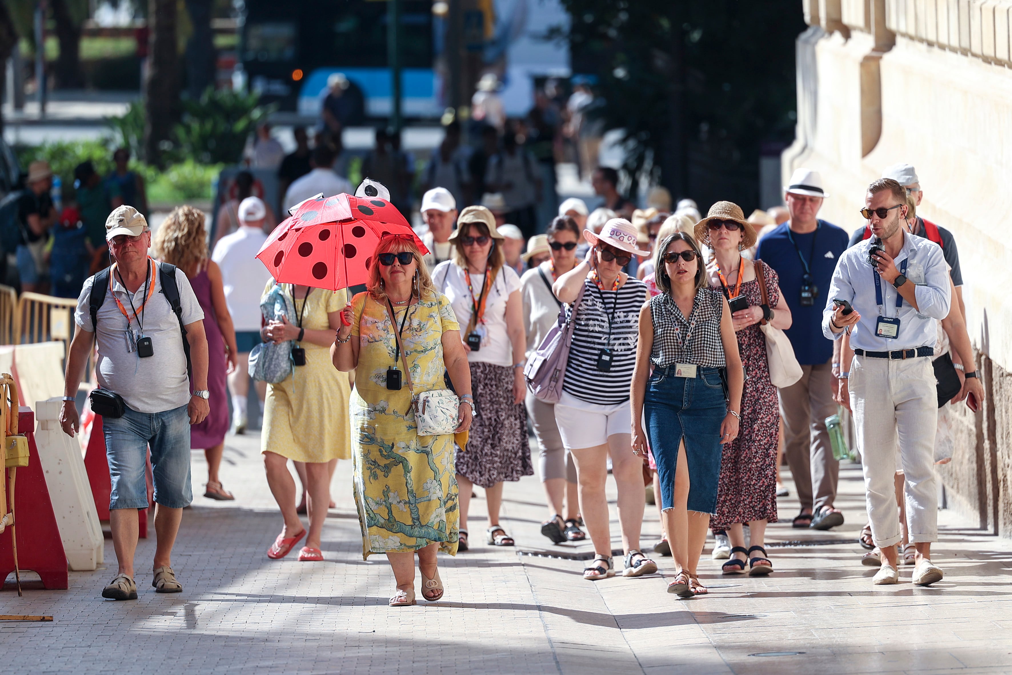Numerosos turistas pasean por el centro histórico de Málaga con sombreros, gorras y abanicos, mientras se refrescan por las fuentes y se resguardan a la sombra por la ola de calor.