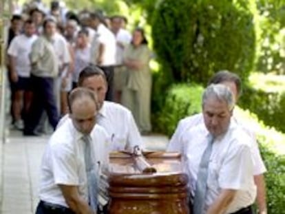 El féretro de una de las víctimas es sacado del edificio tras el levantamiento de los cadáveres.