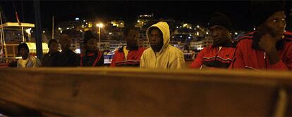 Un grupo de <i>sin papeles</i> aguarda en el puerto tinerfeño de Los Cristianos, tras llegar en una patera.