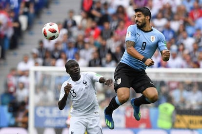 El centrocampista N'Golo Kante y el delantero Luis Suarez luchan por el balón.