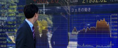 Un hombre de negocios observa una pantalla que muestra indicadores financieros en Tokio (Japón).