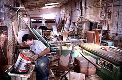 Trabajos de desescombro y limpieza en la carpintería Oliver, situada junto a la N-II e inundada por el aguacero.