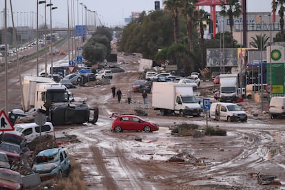 VALENCIA, SPAIN - NOVEMBER 1: People walk by cars and trucks that were among the debris swept up in recent flash flooding along the V-31 highway near the municipality of Massanassa on November 1, 2024 on the outskirts of Valencia, Spain. By late Thursday, Spanish authorities confirmed that at least 150 people had died, mostly in the Valencia region, amid the flooding that swept eastern and southern parts of the country starting on Tuesday. The intense rainfall event is known as a "cold drop" or DANA weather system. (Photo by David Ramos/Getty Images)