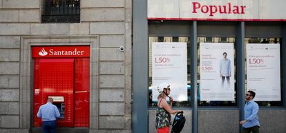 FILE PHOTO: A man uses a cash dispenser at a Santander branch next to a Banco Popular branch in Madrid, Spain.