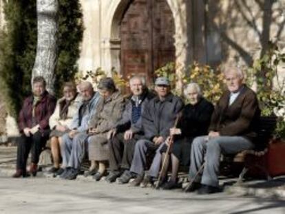 Varios ancianos toman el sol en unos bancos de Olmeda de la Cuesta, Cuenca.