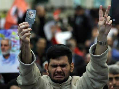 Un iraní muestra el signo de la victoria y sostiene un retrato del asesinado comandante iraní Qasem Soleimani, durante la ceremonia de conmemoración del aniversario de su muerte en la capital iraní, Teherán, el miércoles 3 de enero.