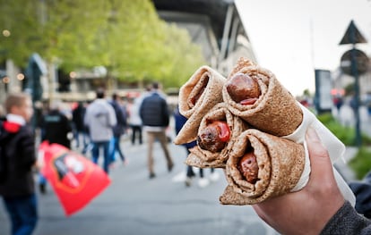 Una persona sujeta cuatro 'galettes saucisse' junto al estadio de fútbol de Rennes (Francia).