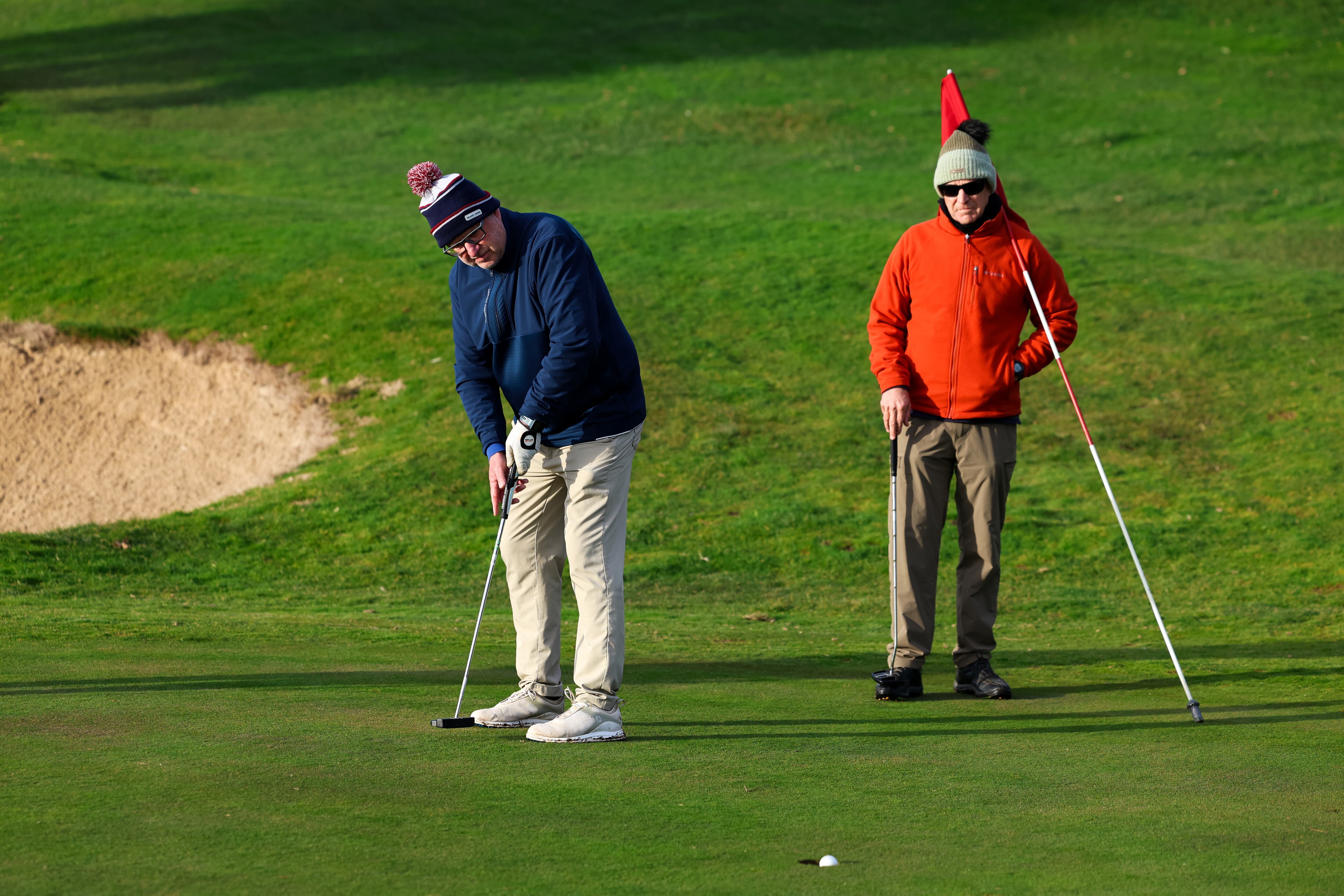 Un miembro del club Los lunes al golf hace su tiro dentro del green.