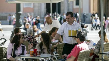 Un camarero sirve bebidas en una terraza en la plaza de la Virgen de Valencia.