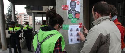 Tres activistas pegan carteles en una protesta de 'escrache', en Lleida.