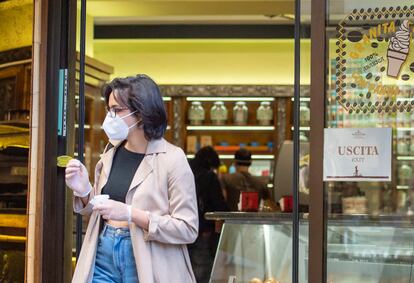 Una joven con mascarilla, tras comprar un café para llevar este lunes en Roma.