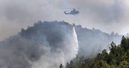 Un helicóptero descarga agua en la zona incendiada.