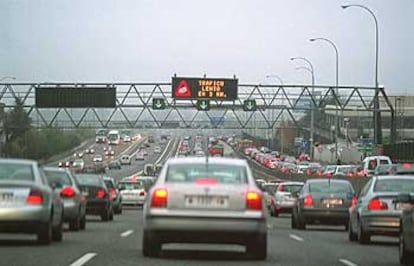 Una larga hilera de automóviles circula con lentitud por la A-6, a la altura de la cuesta de las Perdices. Sobre sus cabezas, un cartel indica que hay tráfico lento a lo largo de tres kilómetros más.