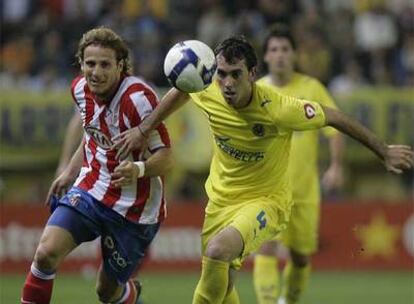 Forlán y Godín persiguen el balón.