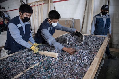 Tres hombres trabajan en una fábrica que recicla ropa usada desechada en el desierto de Atacama para fabricar paneles aislantes de madera para las paredes de viviendas sociales en Iquique (Chile).