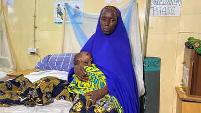 Fatima Usman acuna a su hija, Aisha, en una cama del centro de tratamiento para niños con desnutrición aguda de Damaturu, en Yobe, Nigeria.