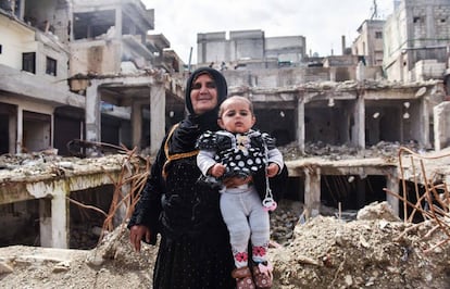 Uma mulher posa com a neta nos escombros de um bairro de Raqa.