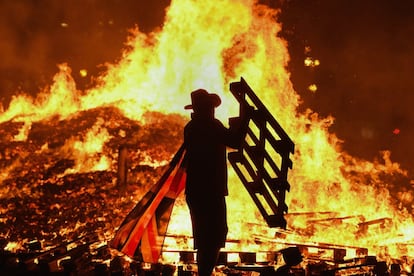 Un hombre aviva una hoguera con motivo de la celebración del '12 de julio' en Belfast (Irlanda del Norte). Las celebraciones comenzaron la pasada noche con las hogueras del 'Once de Julio', las cuales llegan a congregar a cientos de personas en torno a enormes fogatas en barrios protestantes de las grandes ciudades.