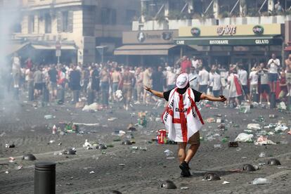 Un hincha con la bandera inglesa pasea en medio de decenas de cristales rotos. 