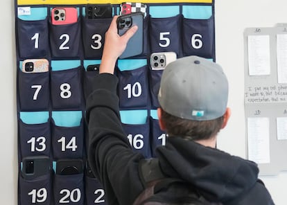 Un estudiante coloca su teléfono en un bolso antes de entrar a clase