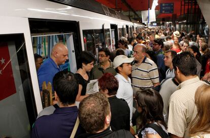 Un grupo de personas sale en la estación de Nuevos Ministerios, mientras otros viajeros espera, llenando el andén, para subir.