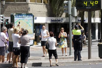 Varios vecinos fotografíaban ayer en la plaza del Ayuntamiento de Valencia un termómetro en el día de mayor calor en la ciudad desde que hay registros.