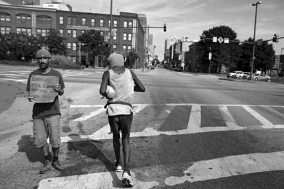 BALTIMORE, MD - SEPTEMBER 15: Keith Boissiere (R) runs past a man holding a sign that reads 'Homeless...Type 1 Diabetes... Anything Helps...God Bless!!' on Martin Luther King Boulevard on September 15, 2016 in Baltimore, Maryland. According to data provided by The City of Baltimore and the Mayor's Office of Human Services, there are an estimated 2,800 homeless in Baltimore. Though only a rumor, the 'Running Man' is not homeless, but does collect government assistance in the form of: Supplemental Security Income, the Food Supplement Program, and Medicaid. He was deemed unfit to work because of his serious health conditions, which include problems with his heart and kidneys. Keith Boissiere has been running nearly every day for the past three decades - averaging more than 20 miles per day - for his health. Many residents only know the enigmatic figure by his nickname of the 'Running Man' - but Boissiere, 64, is a green-card-carrying Trinidad and Tobago native living in Baltimore. Having never competed, nor having a desire to do so, the 'Running Man' held a daily streak of 12 and a half years which helped him earn his alias. But his health took a turn for the worse in 2008 - the streak ended - as his life almost did, too.   Patrick Smith/Getty Images/AFP
== FOR NEWSPAPERS, INTERNET, TELCOS & TELEVISION USE ONLY ==