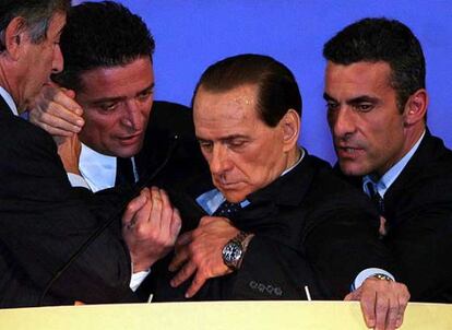 Tres colaboradores sostienen a Berlusconi cuando se desmaya.