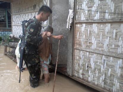 Una anciana es ayudada por un  soldado del Batall&oacute;n de Infanter&iacute;a 71, Brigada de Infanter&iacute;a 1001a del Ej&eacute;rcito filipino en un &aacute;rea inundada en Compostela Valley, sur de Filipinas.