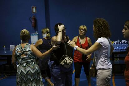 Una mujer que fue evacuada de su casa es consolada por voluntarias en el centro deportivo de Las Lagunas.