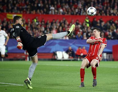 El guardameta del Sevilla David Soria despeja el balón ante la presencia del delantero del Bayern de Múnich Robert Lewandowski