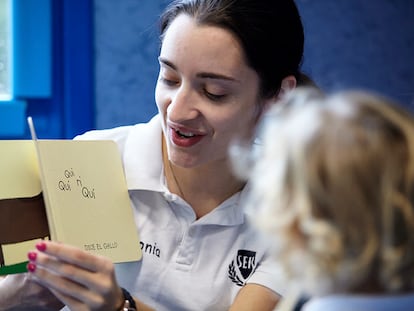 Una alumna mayor cuenta un cuento a una alumna de infantil en uno de los colegios SEK