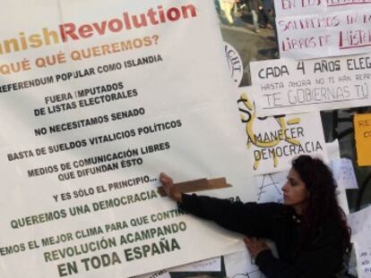 Una joven pega un cartel con las reivindicaciones en la Puerta del Sol.