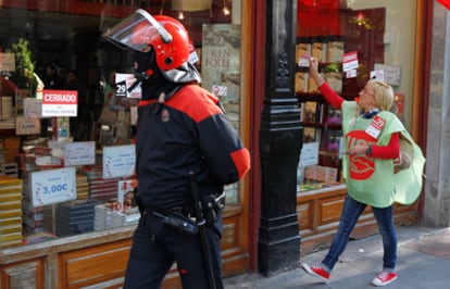 Un agente de la Ertzaintza junto a una militante de UGT que pega pegatinas en una tienda abierta de Bilbao.