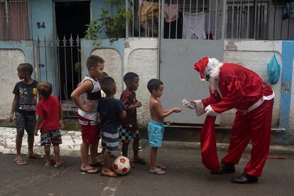 Homem vestido de Papai Noel higieniza as mãos de crianças no complexo de favelas da Maré, Rio de Janeiro, em 23 de dezembro.