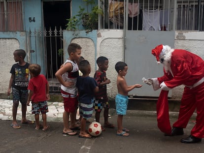 Homem vestido de Papai Noel higieniza as mãos de crianças no complexo de favelas da Maré, Rio de Janeiro, em 23 de dezembro.