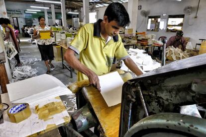 El papel se corta uno a uno en hojas más pequeñas en una máquina rudimentaria de troquelar.