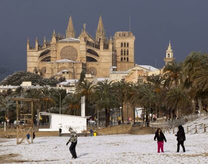 Varias personas juegan en la playa de Palma tras la fuerte nevada que ha caído en Mallorca.