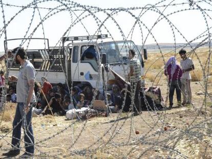 Varios kurdos esperan en la frontera turca despu&eacute;s de haber escapado de Kobane (Siria).