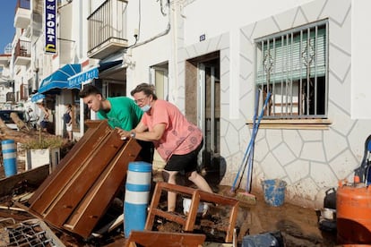 Unos vecinos retiran los muebles dañados tras las inundaciones en Alcanar, este jueves.