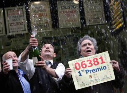 Varios afortunados celebran el <i>gordo</i> del sorteo extraordinario de Navidad en una administración de Madrid.