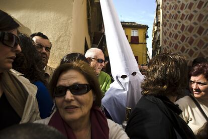 Un nazareno de la cofradía malagueña de Las Fusionadas se abre camino entre la multitud a su llegada al templo.