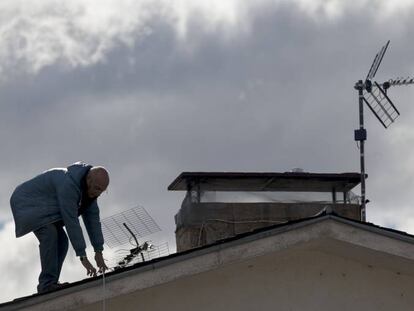 Un operario cambia la antena en el tejado de una vivienda unifamiliar en Manzanares el Real (Madrid). 