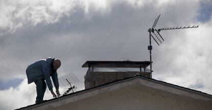 Un operario cambia la antena en el tejado de una vivienda unifamiliar en Manzanares el Real (Madrid).