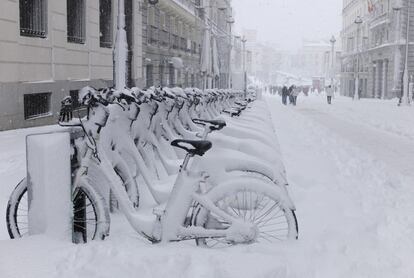 Bicicletas cubiertas de nieve en la calle Alcalá de Madrid. Al fondo, la Puerta del Sol.