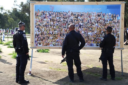 Police officers observe a panel with photos of the victims of the Nova festival before accompanying the hostages' relatives on the march.