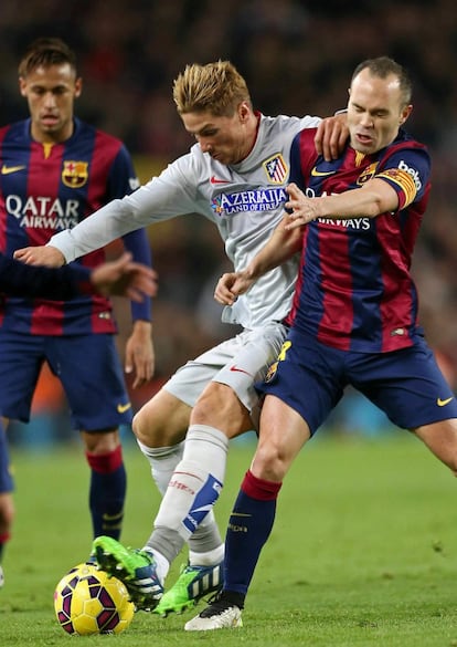 El centrocampista del FC Barcelona Iniesta (d) pelea un balón con Fernando Torres (2-i), del Atlético de Madrid, durante el partido de Liga en Primera División, el 11 de enero de 2015.