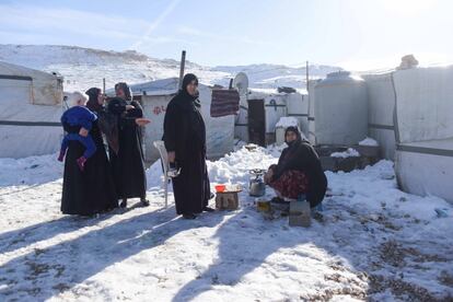 La vecinas de un asentamiento informal en Líbano preparan un infusión de mate a las puertas de sus tiendas entre los restos de nieve tras el paso de la Tempestad Norma.