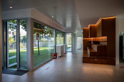 Una zona interior del edificio premiado que da a una terraza con césped y árboles.